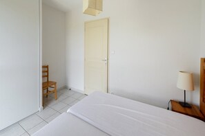 Ein Hotelzimmer mit Bett, Stuhl, Tür und Nachttisch mit Lampe.
