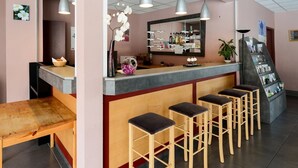 A bar area with a counter, stools, hanging lights, and a mirror. - Residence Vacanceole Le Domaine du Green (Rivieres)