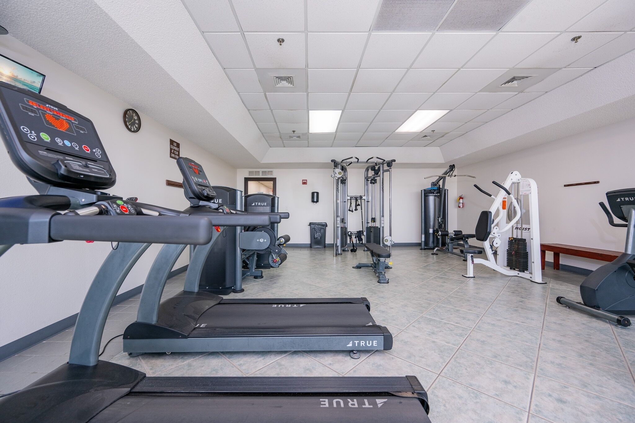 A gym with treadmills, weight machines, and a wall clock.