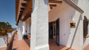 A white building with a tiled patio, wooden beams, and a door with a bull symbol. - House with Spacious Terrace and Private Barbecue (Begur)