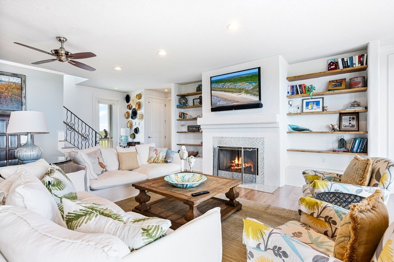 A living room with a fireplace, a television mounted above it, and a bookshelf with books and decorative items.