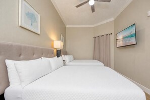 A hotel room with two beds, a ceiling fan, a painting, and a lamp. - Phoenix West 1803 3 Bedroom Condo (Orange Beach)
