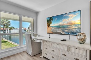 A modern room with a large window, a desk, and a flat-screen TV. - Runaway Bay 276 2 Bedroom Home (Bradenton Beach)