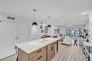 A modern kitchen with a marble countertop, wooden cabinets, pendant lighting, and a view of the outdoors. - Runaway Bay 276 2 Bedroom Home (Bradenton Beach)