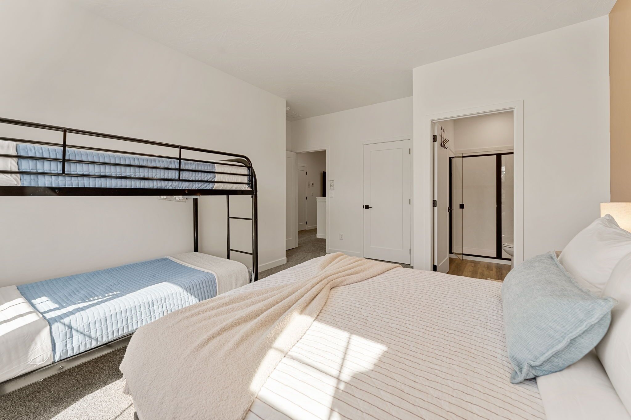 A bedroom with a bunk bed, a single bed, and a wardrobe.