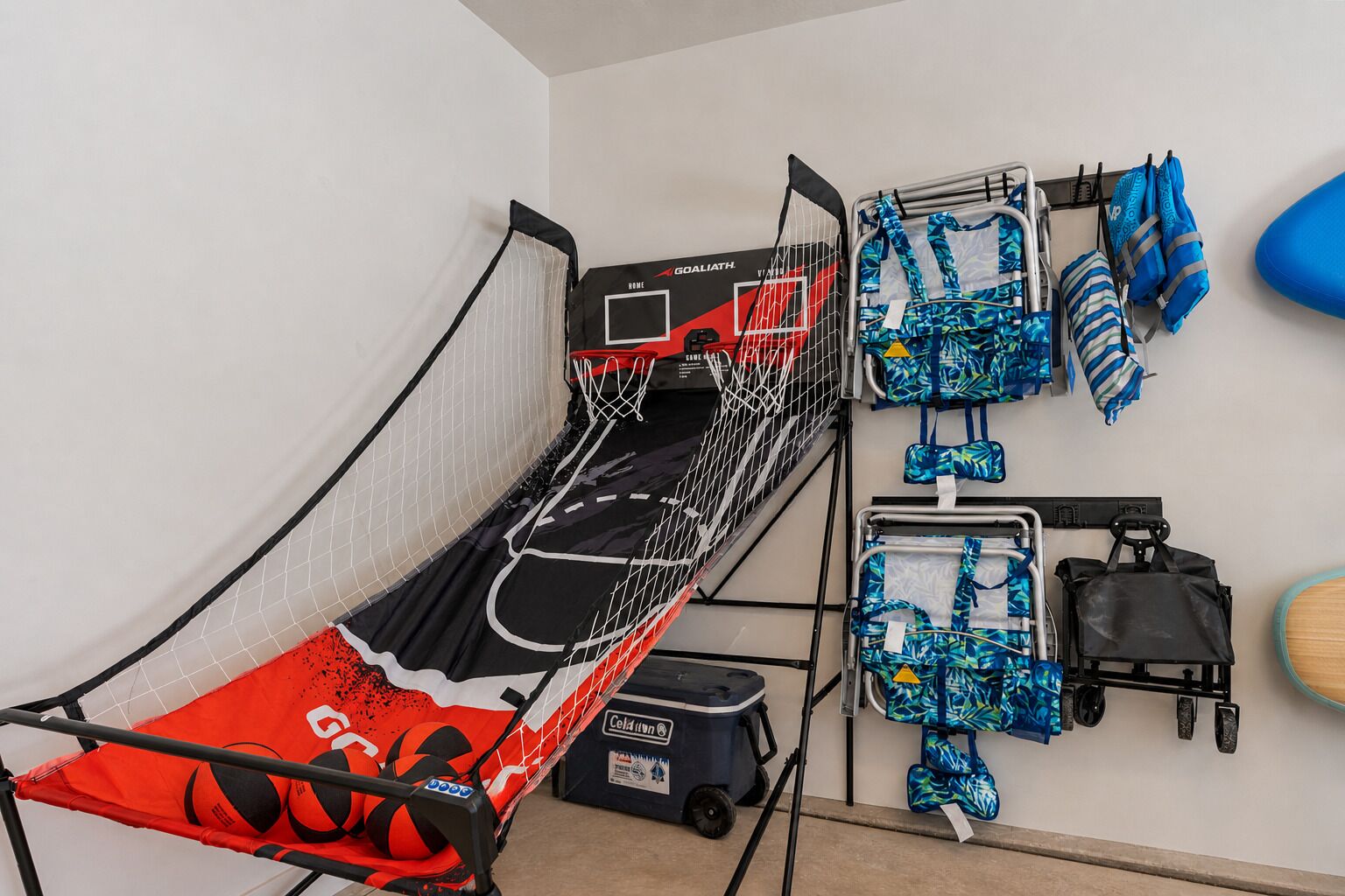 A bunk bed with a basketball hoop, a wall-mounted luggage rack, and a small desk with a computer.