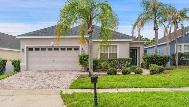 A residential house with a garage, a driveway, and a well-maintained lawn. - Bkd835 4 Bedroom Home (Davenport)