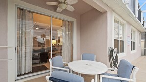 A balcony with a round table and chairs, a ceiling fan, and a sliding glass door leading to an interior space. - Bkd835 4 Bedroom Home (Davenport)