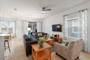 A living room with a sofa, armchair, coffee table, TV, and curtains. - Bkd835 4 Bedroom Home (Davenport)