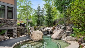 A hot spring area with a pool, rocks, and a waterfall. - Aw K17 2 Bedroom Condo (Snowmass Village)