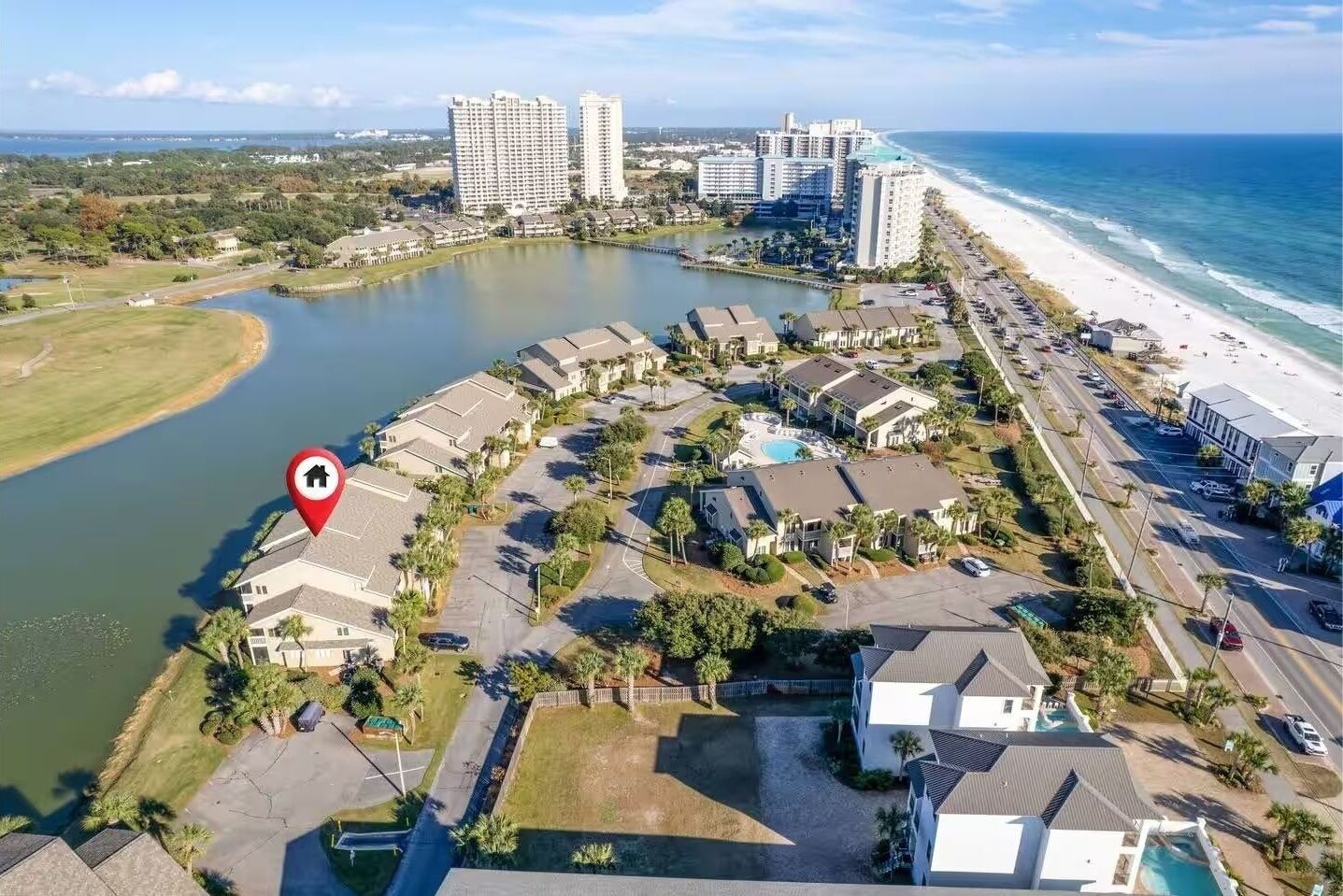 An aerial view of a coastal residential area with a marina, beachfront, and high-rise buildings in the background.