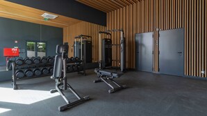 A gym with exercise equipment, a dumbbell rack, and a door. - Calm Luxury w Pool Gym Parking (Lisbon)