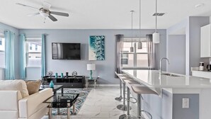 A modern living room with a sofa, a coffee table, a TV, and a painting on the wall. - 4BR Grill Resort Pool Kids Rooms Near Disney 5129 (Kissimmee)
