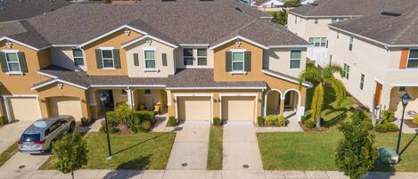 A residential neighborhood with single-family homes, a clear sky, and a car parked in the driveway.