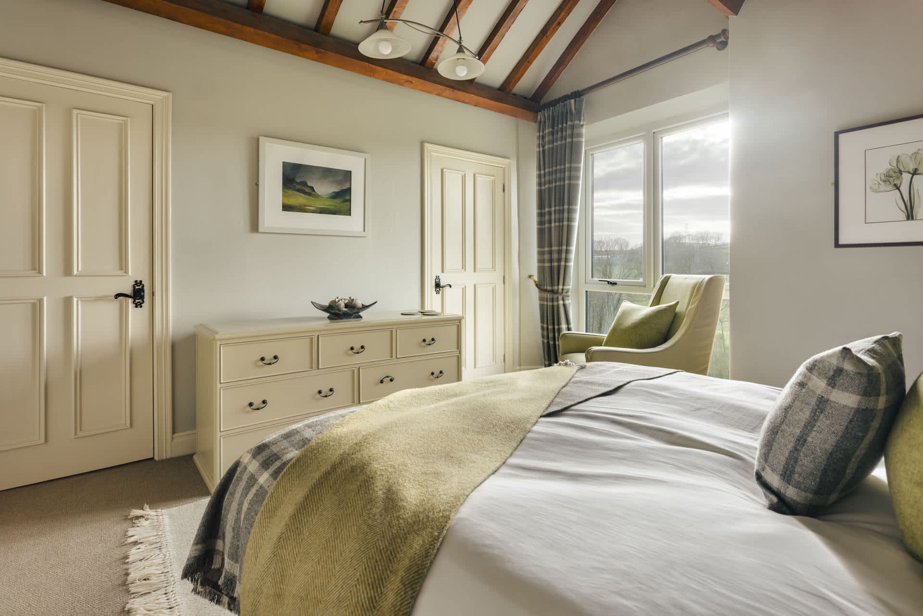 Een slaapkamer met een bed, een kaptafel, een stoel en een raam met gordijnen.