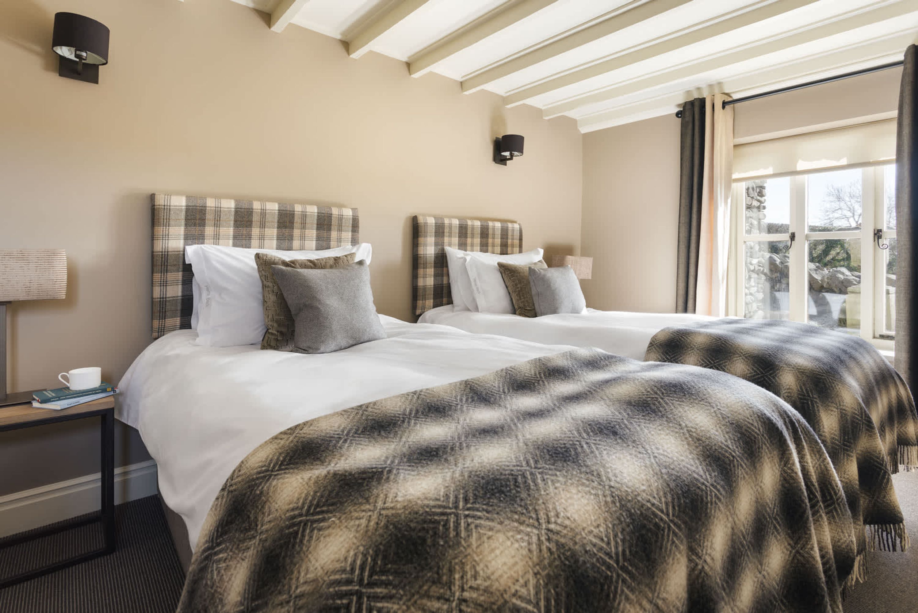 Une chambre d’hôtel avec deux lits, une fenêtre avec des rideaux, une lampe sur la table de chevet et une vue sur l’extérieur.