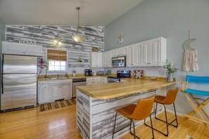 A modern kitchen with white cabinets, a wooden island, and a stainless steel refrigerator. - The Beach Peach – Oceanfront Escape with Panoramic Views (North Topsail Beach)
