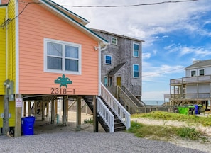 A beach house with a staircase leading to a deck, a beach pier, and a sign indicating 'The Beach House.' - The Beach Peach – Oceanfront Escape with Panoramic Views (North Topsail Beach)