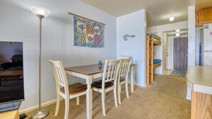 A compact room with a dining table, chairs, a floor lamp, a bunk bed, and a refrigerator. - Oceanfront Escape at Surf Condo 814 – Relaxation Starts Here (Surf City)