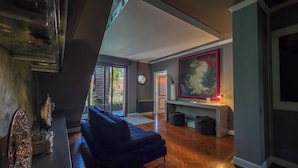 Un salon moderne avec un canapé bleu foncé, un grand tableau abstrait et un parquet en bois disposé en chevrons.