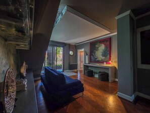Ein modernes Wohnzimmer mit einem dunkelblauen Sofa, einem großen abstrakten Gemälde und einem Holzboden mit Fischgrätmuster.
