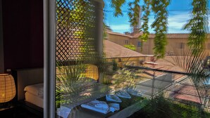 Une chambre avec un lit, une fenêtre et une vue sur des immeubles et des arbres.
