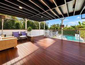 An outdoor deck with a pool, a basketball hoop, and a covered seating area. - West End Oasis: 4BR w/ Full amenities and Pool (Brisbane)