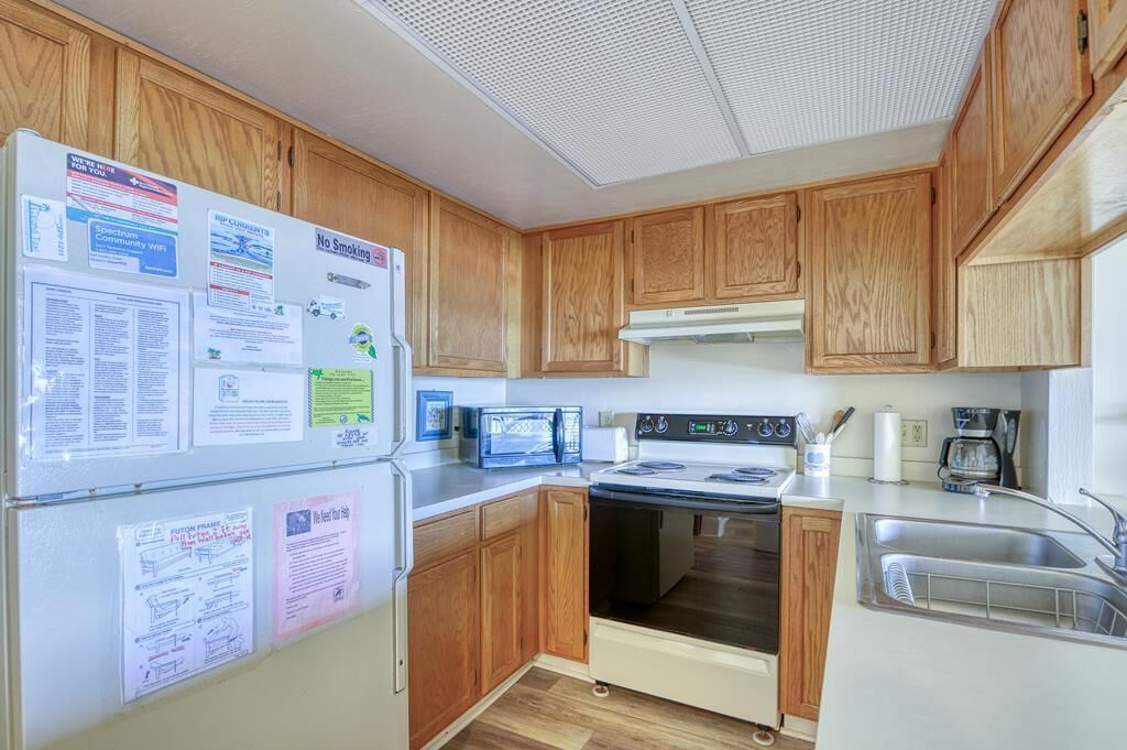 A compact kitchen with wooden cabinets, a microwave, an oven, and a sink.