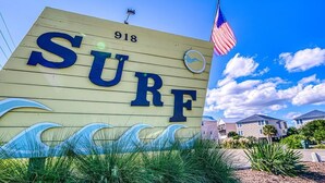 A sign with the word 'SURF' and the number '918' on a wooden background, with an American flag and a small circular emblem. - Oceanfront Condo – Surf City, NC (Surf City)