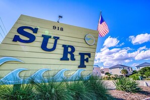 A sign with the word 'SURF' and the number '918' on a wooden background, with an American flag and a small circular emblem. - Oceanfront Condo – Surf City, NC (Surf City)