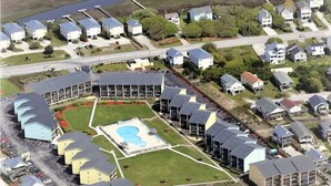 An aerial view of a coastal residential area with houses, a large swimming pool, and a beach. - Oceanfront Condo – Surf City, NC (Surf City)