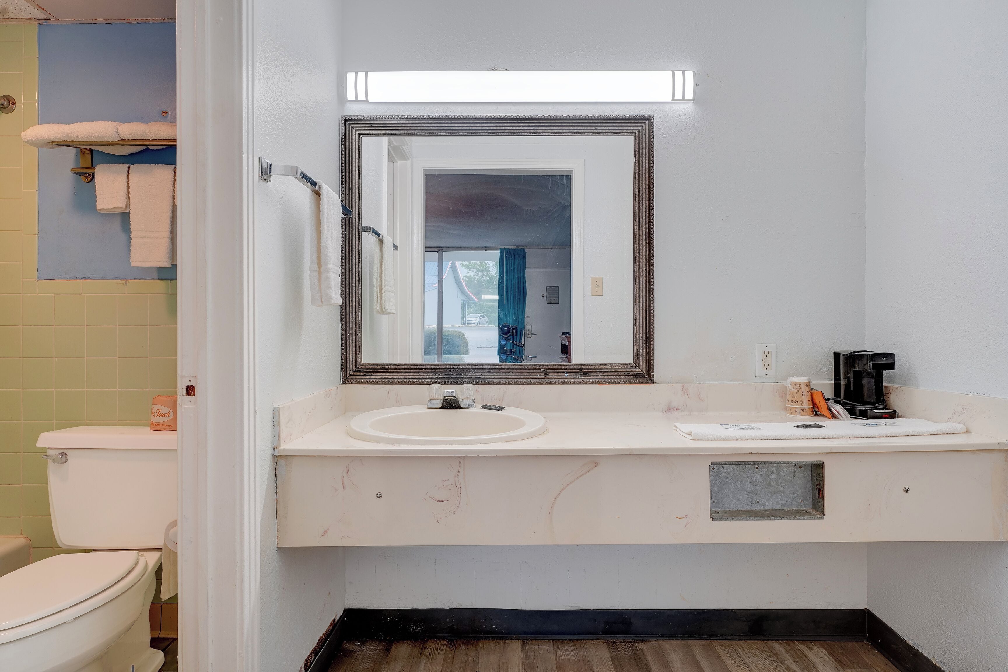 A bathroom with a toilet, sink, mirror, and towel rack.