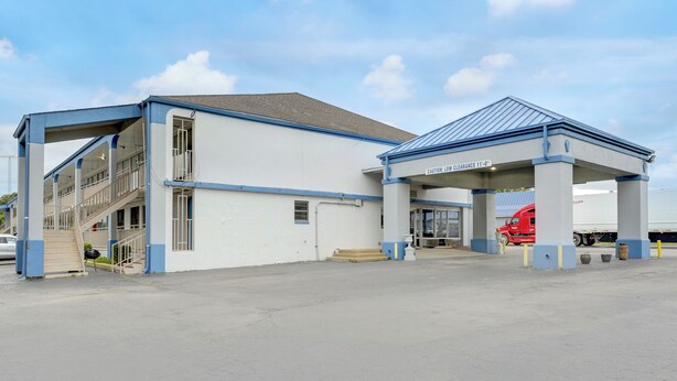 A building with a covered entrance, a staircase, and a truck parked outside.