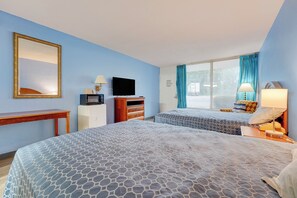Una habitación de hotel con cama, televisión, escritorio, cómoda y ventana con cortinas.