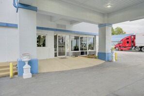A building with a covered entrance, a truck parked outside, and a clear sky.