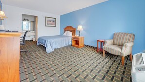 A hotel room with a bed, a chair, a desk, a lamp, and a heater. - Ole South Inn Jackson I 40 TN (Denmark)