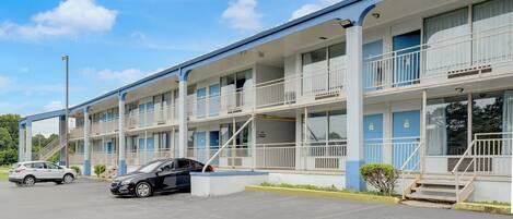 A motel with multiple floors, balconies, and a parking lot.