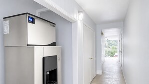 A hallway with a built-in refrigerator and a water dispenser, leading to a door with a view of a balcony.