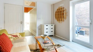 Ein Wohnzimmer mit einer Couch, einem Couchtisch, einem weißen Schrank und einem großen Fenster mit Blick auf eine Backsteinmauer.