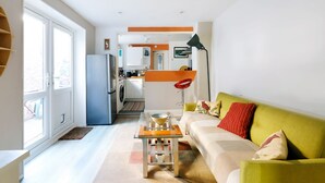 Eine moderne Wohnung mit Küche, Essbereich und einem grünen Sofa mit Kissen.