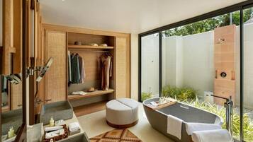 A modern bathroom with a bathtub, a shower area, a vanity with a mirror, and a seating area with a rug.