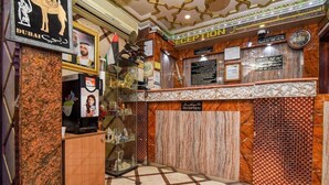 Un'area reception con una scrivania in marmo, quadri appesi, un orologio e una segnaletica con i prezzi delle camere.