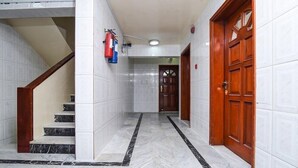 Un corridoio con pavimento in marmo, una porta in legno e una scalinata con gradini in marmo.