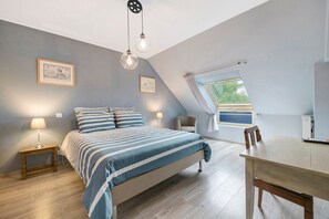 Een slaapkamer met een bed, nachtkastjes, een bureau en een raam.