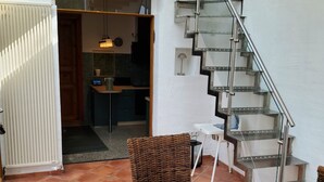 A dining area with a wooden table, wicker chairs, and a glass staircase. - Built in 1920, a house with a two-story sunroom, just a short drive from the North Sea  (Ostrohe)