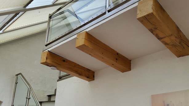 A modern interior with a glass staircase, wooden beams, and a colorful abstract painting. - Built in 1920, a house with a two-story sunroom, just a short drive from the North Sea  (Ostrohe)