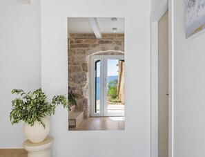 Ein Zimmer mit Steinwand, einer zur Balkon mit Aussicht führenden Tür und einem Blumentopf.