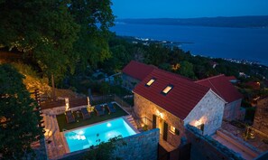 Ein Gebäude aus Stein mit Swimmingpool, rotem Dach und Meerblick.