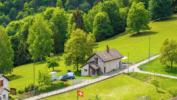 A rural landscape with a small house, a flag, and a road. - Casa Eyrie Centovalli 3BR Chalet (Centovalli)