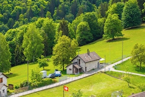 Un paysage rural avec une petite maison, un drapeau et une route.